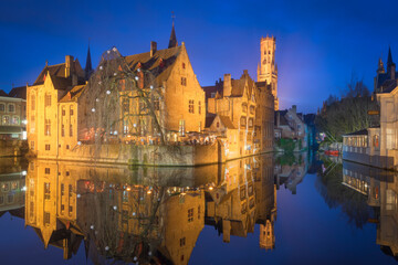 Scenic view of houses and Belfry reflecting in canal water at night