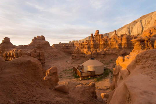 View of yurt in valley of red rock cliff during sunrise
