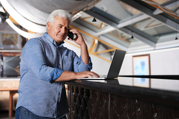 Senior business owner talking on phone in his restaurant