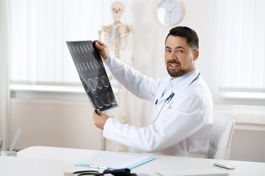 Orthopedist examining X-ray picture at desk in clinic