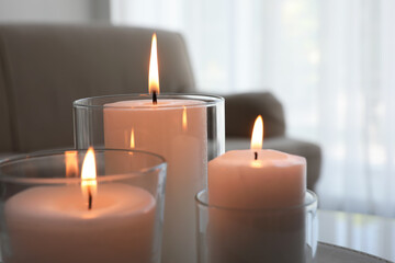 Obraz na płótnie Canvas Burning candles in glass holders indoors, closeup
