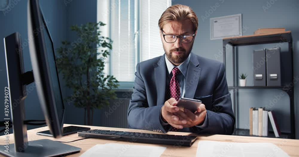 Poster busy office worker in formal outfit and eyeglasses using smartphone and computer for work at own off