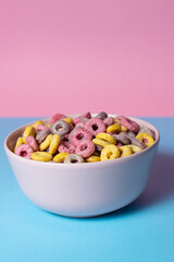 Isolated bowl of mixed cereals and marshmallows on a blue and pink background