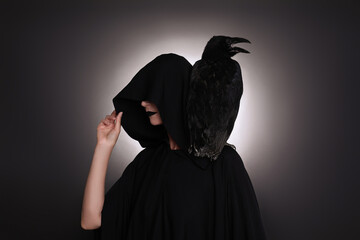 Mysterious witch with raven on black background