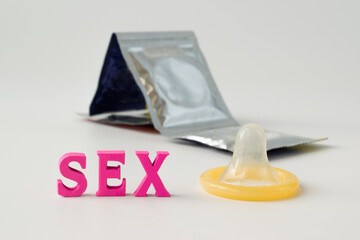 Yellow condom and the word sex on a white background.