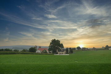 Fototapeta na wymiar Meadow, field with houses in the background. Sunset over a village. Rural scenery