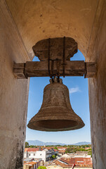 Fototapeta premium Leon, Nicaragua - November 27, 2008: Cathedral of Assumption, Asuncion.. Closeup of heavy old bell hanging in part of the towers. Lookout on the town with mountains on horizon, under blue sky.