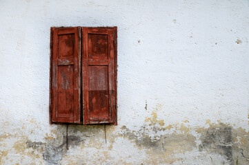 Old wooden red window with half open shutters and house wall background