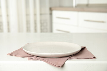 Empty plate and napkin on white table indoors