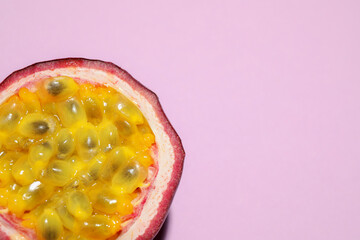 Half of passion fruit (maracuya) on pink background, top view. Space for text