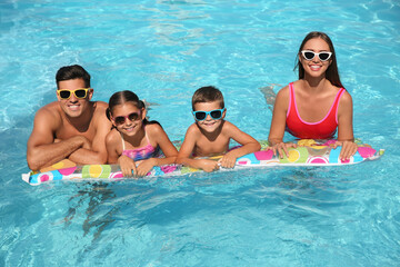 Happy family on inflatable mattress in swimming pool