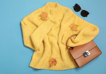 Flat lay composition with sweater and dry leaves on light blue background. Autumn season