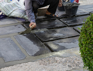 Construction workers are paving the sidewalk stone with cement.