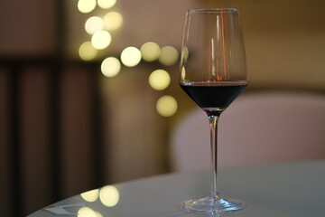 close up a glass of red wine on table at night with golden bokeh 