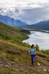 Naklejka premium Adventurous Girl Hiking up the Nares Mountain during a cloudy and sunny evening. Taken at Carcross, near Whitehorse, Yukon, Canada.