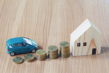 Car and a toy house placed beside the coin on the wooden floor.