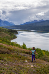 Adventurous Girl Hiking up the Nares Mountain during a cloudy and sunny evening. Taken at Carcross, near Whitehorse, Yukon, Canada.