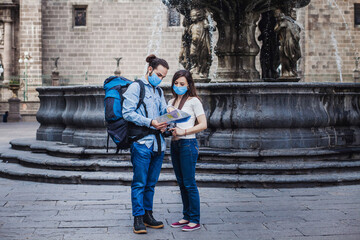 Fototapeta na wymiar latin young couple tourists with face mask on vacation in Mexico Latin America in coronavirus pandemic