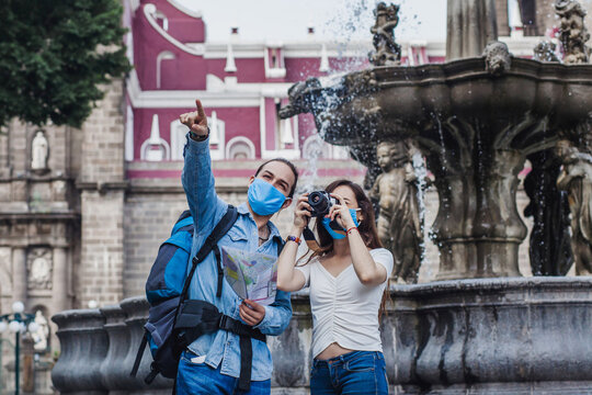 Latin Couple of tourists exploring a colonial city together and with face mask and making photo on vacation in coronavirus pandemic in Mexico 