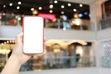 Hand of a man holding smartphone device in the Shopping mall background.