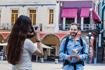 Tourists taking pictures on vacation in a historical latin american city holding a camera