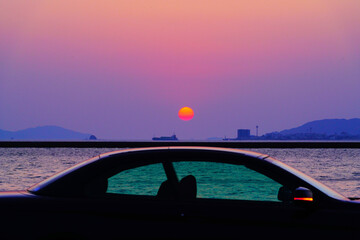 車と夕陽と船