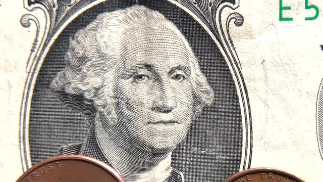 4K HD video of Zooming out from President Washington's face on the one dollar bill to half the face of the bill with pennies below. Money, minimum wage, financial theme
