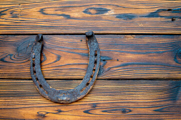 Old used rusty horseshoe on rustic wooden background. Lucky symbol. St. Patrick's Day celebration