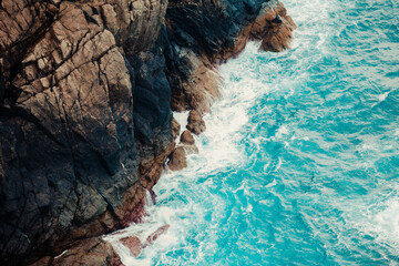 Aerial shot of the crystal water sea touching the rocks of the bottom of a mountain © Banana Images