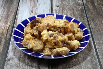Traditional deep fried chopped pork belly with flour on the plate. Famous crispy and crunchy snack in Asia restaurant. 