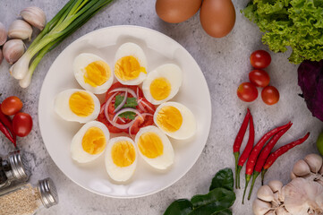 Half boiled egg in a white plate with tomatoes and spring onions.