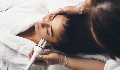 Anti aging procedures for facial skin in a modern spa salon done to a brunette woman with new apparatus