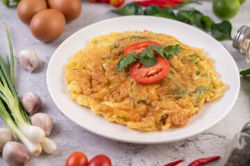 Omelet in a white plate garnished with tomatoes and coriander.