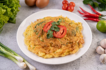 Omelet in a white plate garnished with tomatoes and coriander.