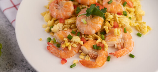 Stir fried eggs with shrimp on a white plate.