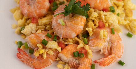 Stir fried eggs with shrimp on a white plate.