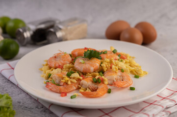 Stir fried eggs with shrimp on a white plate.