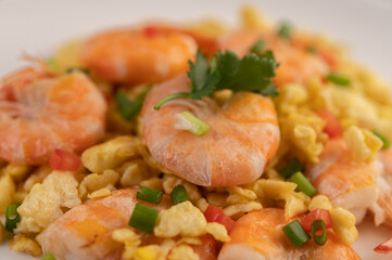 Stir fried eggs with shrimp on a white plate.