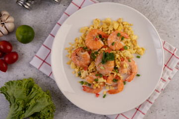 Stir fried eggs with shrimp on a white plate.