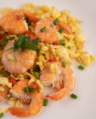 Stir fried eggs with shrimp on a white plate.