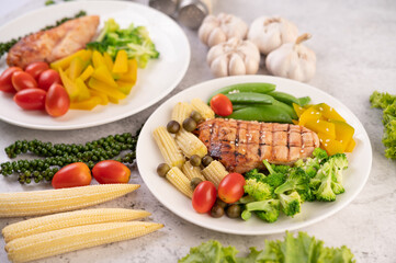 Chicken steak topped with white sesame, peas, tomatoes, broccoli and pumpkin in a white plate.