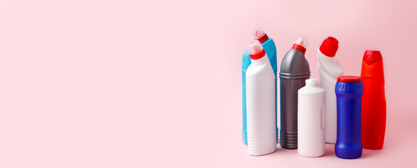 Cleaning products banner on pink background, copy space, concpet of house cleaning service, sanitize, antibacterial housework, bright bottles and washing tools, domestic chemical set