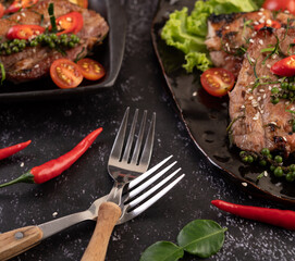 Place a fork on top of each other with chili and kaffir lime leaves on a black background.