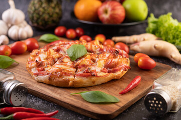 Pizza in a wooden tray with tomatoes Chili and basil.