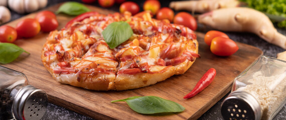 Pizza in a wooden tray with tomatoes Chili and basil.