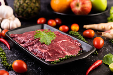 Sliced ​​raw pork used for cooking with chili, tomato, basil, and fresh pepper seeds.
