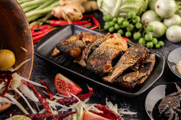 Deep-fried fish slices in a black plate.