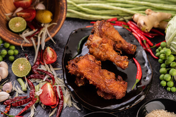 Three pieces of fried chicken on a black plate.