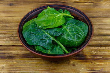 Fresh green spinach leaves in bowl on a wooden table