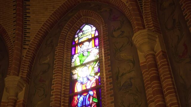 Stained glass window in church, downward tilt reveal up shot